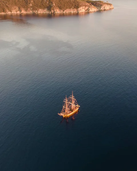 Aerial view of a pirate vessel sailing along the coast at sunset in Capo D\'Enfola, Elba Island, Tuscany, Italy.