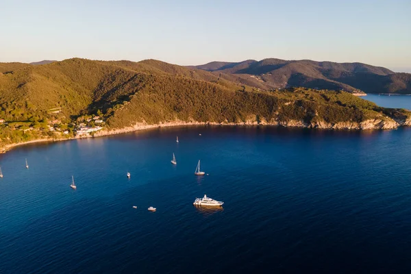 Aerial view of sailing boats along the coast at sunset, Enfola, Portoferraio, Elba Island, Tuscany, Italy.