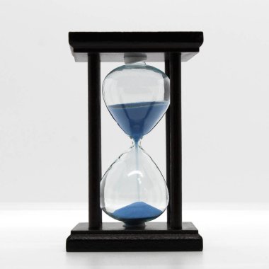 Kum saati ince mavi kum, orta tahtadan vücut, beyaz arka plan, şeffaf cam gövde.