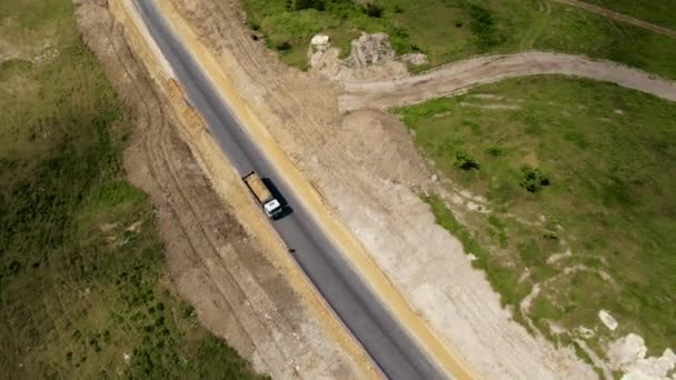 Εναέρια άποψη βαριά εξόρυξη τεσσάρων αξόνων λευκό χωματερή φορτηγών χύνει άμμο από το σώμα για την κατασκευή νέου ασφαλτοστρωμένου δρόμου — Αρχείο Βίντεο