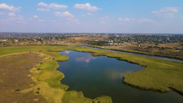 Drone vuela sobre hermoso río y lago con reflexión sobre el agua y muchos edificios del pueblo en la colina — Vídeo de stock