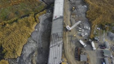 Yüksek vinçli inşaat alanı, kamyonlarda beton mikserler ve yeni beton köprü yapımında işçiler