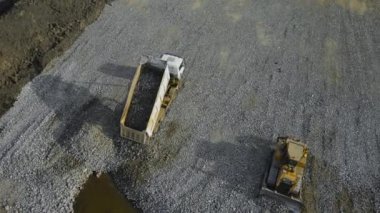 Güçlü bir damperli kamyon taş ve buldozer boşaltarak granit moloz yapımında kullanılıyor.
