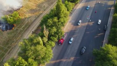 Cesur itfaiyeciler otobanda duman bulutları ve itfaiye aracıyla yanan alevlerle savaşmak için acele ediyorlar.