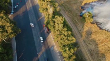 İtfaiyeciler, otoban yakınlarında hareket halindeki arabalarla yanan büyük alevleri söndürmek için yangın hortumlarını çekiyorlar.