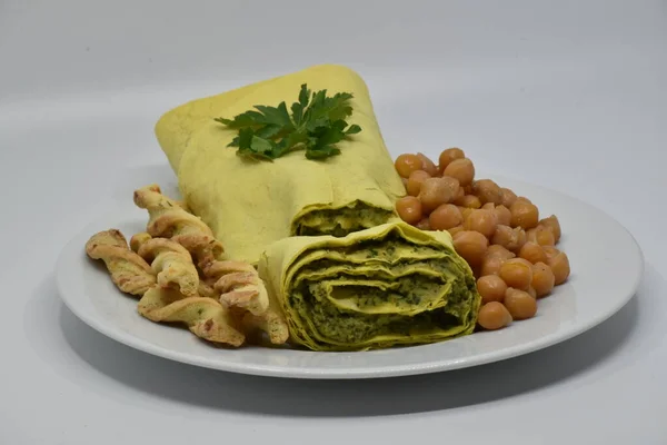 Nohut humusu ve gri bir tabakta otlarla yuvarlan. Yakınlarda nohut ve tuzlu hamur çubukları var..