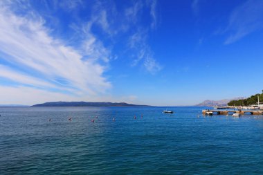 Mavi gökyüzü, denizin üstünde beyaz bulutlar