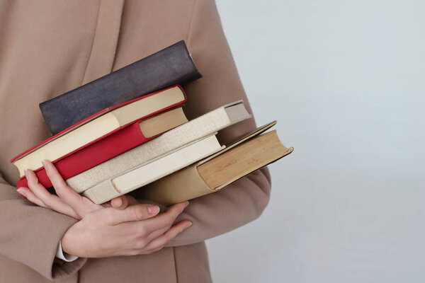 A young beautiful girl holding books in her hands