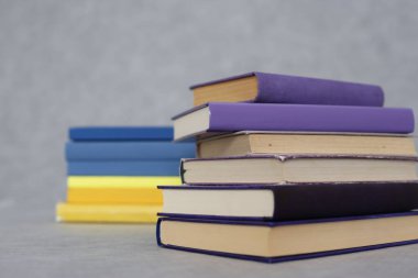 Gri arkaplanda mor kitap yığını