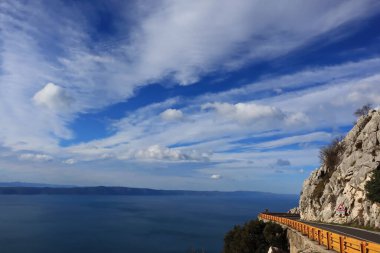 Mavi gökyüzü, denizin üstünde beyaz bulutlar