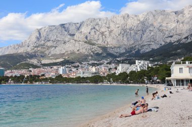 Makarska, Hırvatistan, 18 Nisan 2022. Bu yıl Paskalya tatilini Makarska 'da geçiren ilk turistler, kumsalda güneşlenmenin keyfini çıkarıyorlar.