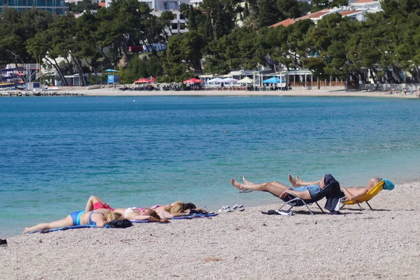 Makarska, Hırvatistan, 18 Nisan 2022. Bu yıl Paskalya tatilini Makarska 'da geçiren ilk turistler, kumsalda güneşlenmenin keyfini çıkarıyorlar.