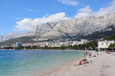 Makarska, Croatia, 12.05.2022. Tourists enjoy the sunny weather on the beach by the sea