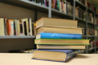Kütüphanedeki ahşap masada yığınla kitap.