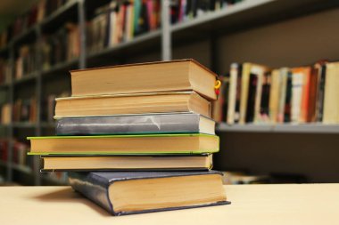 Kütüphanedeki ahşap masada yığınla kitap.