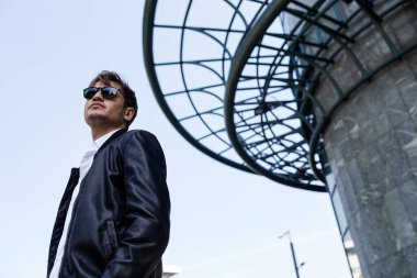 Güneş gözlüklü ve deri ceket giyen yakışıklı bir genç. Açık hava erkek portresi.