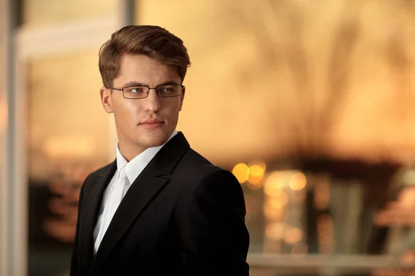 Portrait of a handsome businessman in eyeglasses and black suit, sunset background. Space for text. — Stock Photo, Image