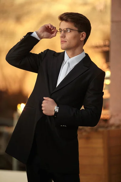 Portrait of a handsome businessman posing in eyeglasses and black suit, wear watch on his hand. — Stock Photo, Image