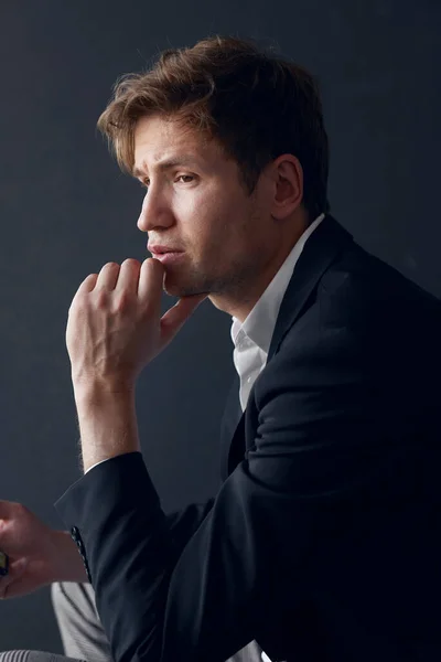 Profile portrait of a handsome young businessman in elegant suit, over black background. — Stock Photo, Image