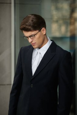 Gözlüklü, siyah takım elbiseli, beyaz kravatlı ve gömlekli yakışıklı bir esmer işadamının profil portresi..