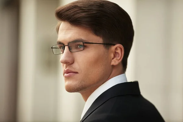 Closeup profile portrait of a handsome businessman in eyeglasses and black suit and white tie and shirt. — Stock Photo, Image