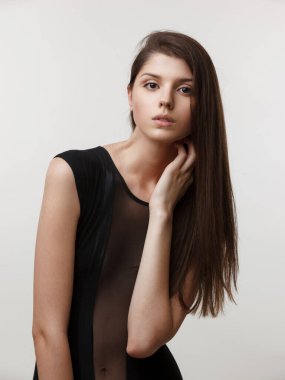 Stüdyoda, beyaz arka planda siyah bir beden giyen bir mankenin güzel portresinin dikey görüntüsü..