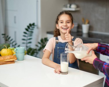Mutfakta bir bardak sütle gülümseyen küçük kız..