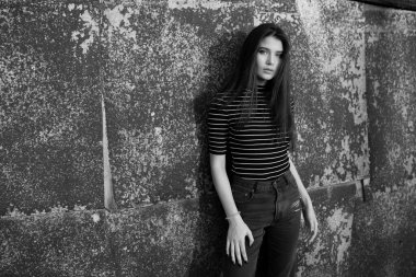 Siyah beyaz fotoğraf. Düz saçlı, kameraya bakan genç bir kızın ön görüntüsü..