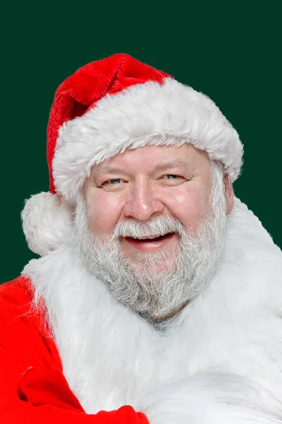 Imagen de primer plano de un feliz Santa Claus riendo vestido con un abrigo rojo y un sombrero, fondo verde aislado. — Foto de Stock