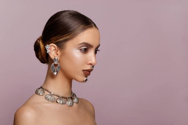 Yatay görüş. Kadın portresi. Koyu pembe arka planda, başka tarafa bakan, mücevher takmış zarif esmer bir kadının güzel portresi. Metin için boşluk.