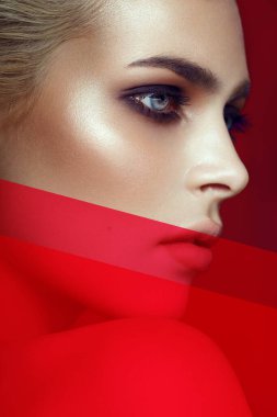 Parlak makyajlı, genç, seksi sarışın modelin yakın plan çekimi. Smokey eyes, artistik imaj, kırmızı ışık. Güzellik konsepti. Dikey görünüm.