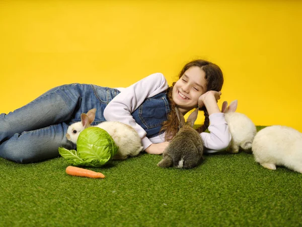 Skolflicka Ligger Och Leker Med Kaninerna Studion Gul Bakgrund — Stockfoto