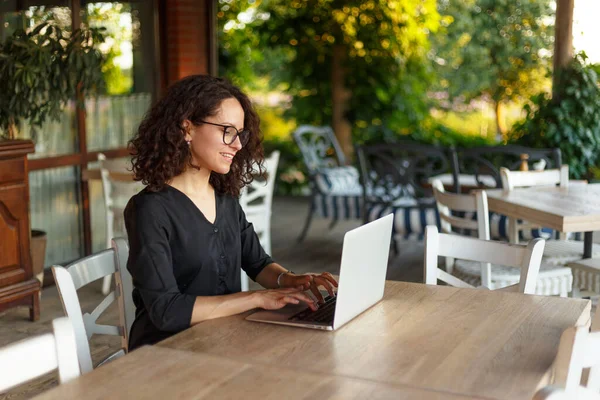 Terasta Otururken Dizüstü Bilgisayarda Çalışan Neşeli Genç Bir Kadın — Stok fotoğraf