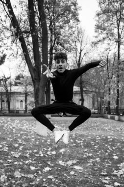 Karizmatik genç dansçı, zıplıyor, kameraya bakıyor. Siyah beyaz fotoğraf.