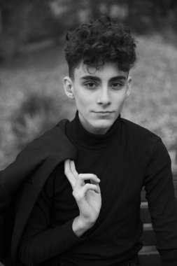 Resmi giyinmiş yakışıklı bir adam modern saç kesimli bir bankta oturuyor..