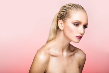 Güzel makyajlı, saçı düzleştirilmiş ve arka planda kalmış pembe bir kadının yan görüntüsü..