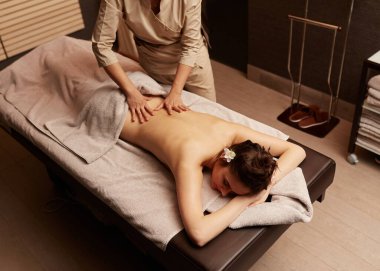 Bir masözün üst görünüşü genç bir kadına vücut masajı yapar. Spa rahatlama kavramı.