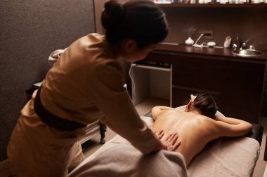 Bir masözün arka görünüşü genç bir kadına vücut masajı yapar. Spa rahatlama kavramı.