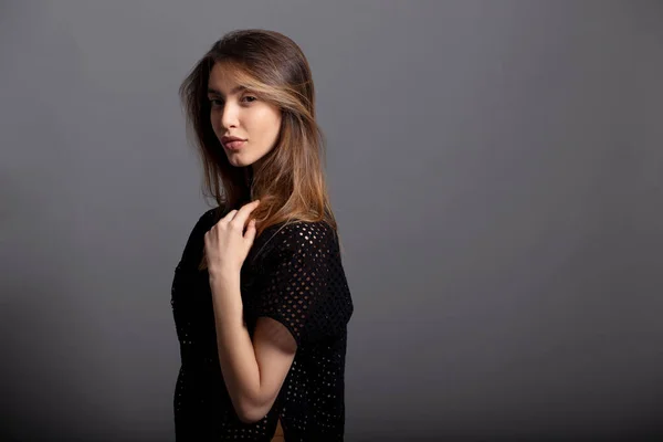 Frontal portrait of a sensual girl with natural makeup, isolated on a grey background.