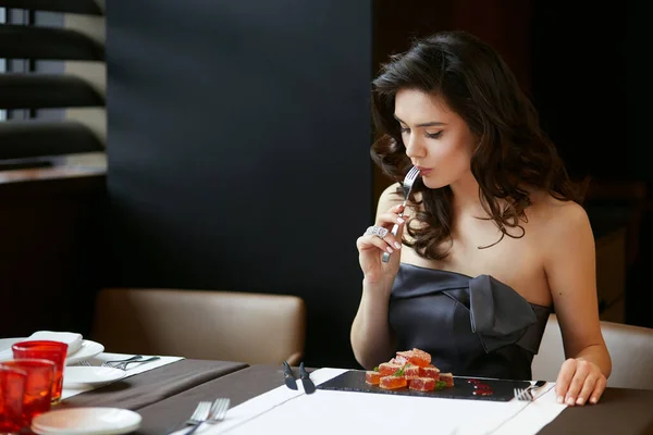 Cheerful girl in dress, serves a dessert in the restaurant, wear in a dress with bare shoulders, makeup and hairstyle.