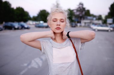 Sarışın, poz veren ve kameraya bakan, el ele tutuşan genç bir kadın resmi..