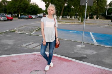 Düşünceli, sarışın, poz veren ve kameraya bakan genç bir kadın..