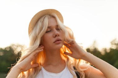 Sarışın, kıvırcık saçlı ve hasır şapkalı güzel bir kadının ön portresini kapat..