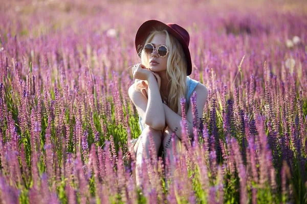 Hipster Blonde Girl Wearing Hat Sunglasses Seated Floral Field Sunset — Fotografia de Stock