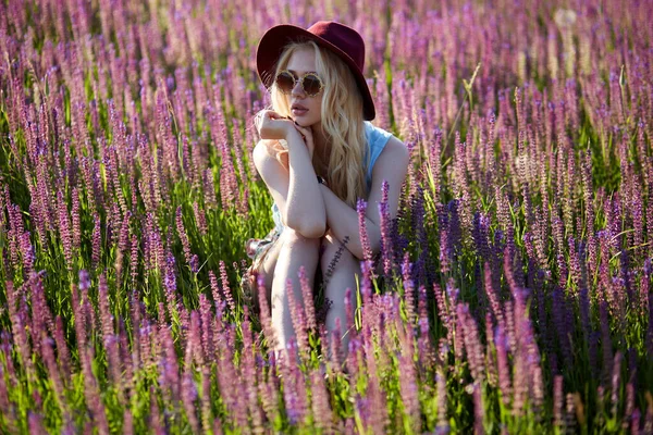 Hipster Girl Wearing Hat Sunglasses Seated Floral Field Sunset Background — Fotografia de Stock