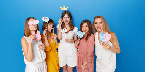 Front image of a group of joyful women to have gender reveals envent, isolated blue background.