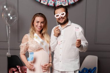 Gülümseyen bir çiftin ön portresi cinsiyet ayrımcılığı sırasında kız ya da erkek yazıtları taşıdığını ve maske taktığını gösteriyor..