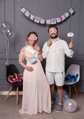 Cinsiyet ayrımcılığı sırasında elinde yazı tutan gülümseyen bir çiftin tam boy fotoğrafı konfeti ve balonların üzerindeki partiyi ortaya çıkarıyor..