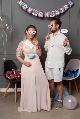 Cinsiyet ayrımcılığı sırasında el yazması erkek ya da kız tutan mutlu bir çiftin tam boy fotoğrafı konfeti ve balonların üzerindeki partiyi gözler önüne seriyor..