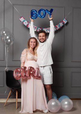 Cinsiyet ayrımcılığı sırasında yazıt tutan bir çiftin tam boy görüntüsü balonların üzerinde parti olduğunu gösteriyor..